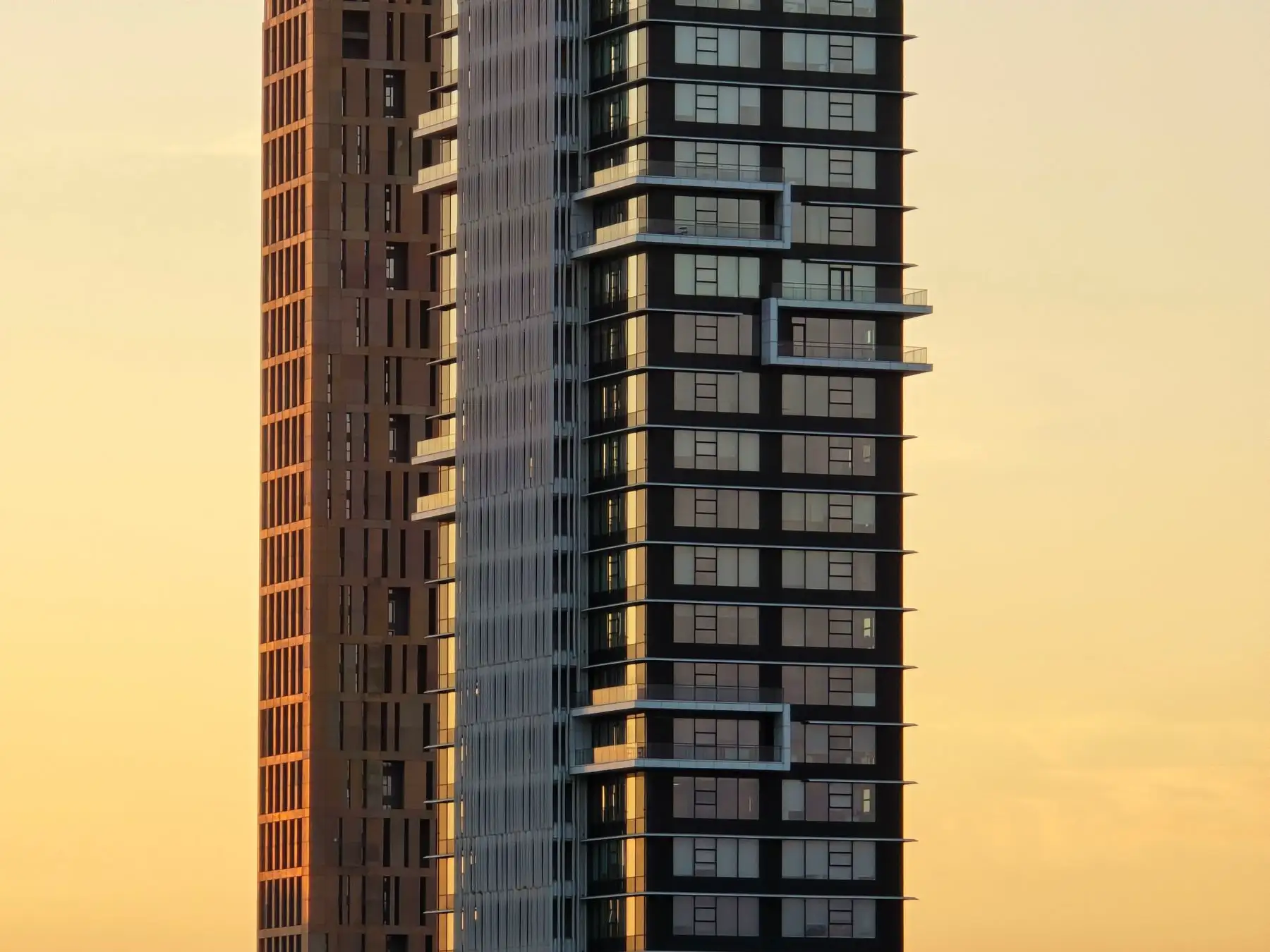 Two residential towers lit gold by the evening sun